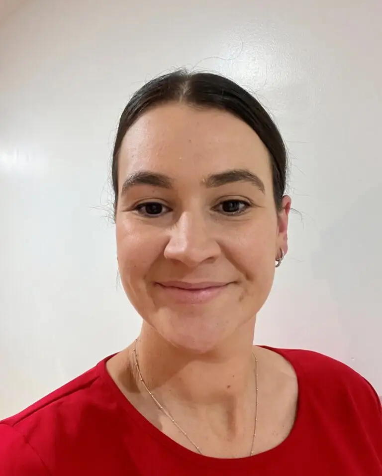 Smiling woman wearing red shirt against white wall